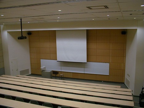 University lecture hall with ceiling mounted projector and recessed electric screen